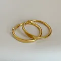 Detailansicht der polierten goldenen Creolen mit minimalistischem rundem Design - Gold