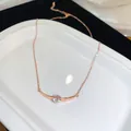 Nahaufnahme einer roségoldenen Halskette mit gebogenem Anhänger und funkelndem Zirkoniastein. - Gebogener Anhänger Schlüsselbeinkette / Roségold