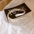 Detailed close-up of a silver-toned heavy metal winding open bangle with engraved text. - Shiny Style (2#)