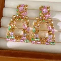 Gedetailleerde close-up van vintage veelkleurige kristallen oorbellen in een juwelendoos - Zilveren Stift Vierkant Hol Stijl / Roze Bruin Groen