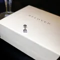 Gros plan d'une boucle d'oreille en zircone étincelante sur une boîte cadeau blanche - 5mm / Blanc