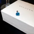 Gros plan d'une boucle d'oreille en zircon bleu sur un coffret cadeau blanc avec fermoir à vis - 7mm / Bleu