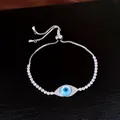Détail macro d'un bracelet réglable en argent orné d'un œil maléfique pavé de zircons. - Argent-Bleu