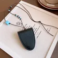 Détail d'un collier pendentif en cuir noir avec perles bleues sur fond de toile artistique - Noir & Bleu