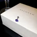 Détail d'une boucle d'oreille en zircon violet sur un coffret cadeau blanc texturé chic - 5mm / Violet