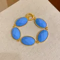 Detail view of gold-tone bracelet with faceted blue oval resin stones in vintage style. - Blue