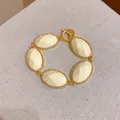 Detailed view of a vintage luxury gold-tone bracelet with cream oval resin inserts. - White