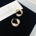 Détail des boucles d'oreilles créoles dorées de style français avec zircons - Or