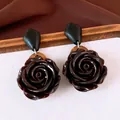 Detail van vintage hars rozen oorbellen met houten accenten en een glanzende afwerking - Zwart en Koffie