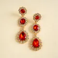 Vue détaillée des boucles d'oreilles vintage dorées avec des cristaux rouges en forme de goutte - Rouge