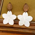 Detaillierte Makroansicht von weißen Blumenohrringen mit Naturholzperlen auf Vintage-Hintergrund - Blumenohrringe (Silber-Ohrringstift) / Kaffee-Weiß