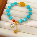 Detailansicht eines Türkis-Perlenarmbands mit 24 Karat vergoldeten Zirkonia-Anhängern. - Kürbis-Anhänger-Stil / Blau