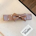 Detailed view of a brown satin ribbon bow hair clip decorated with five sparkling rhinestones - Bowknot Duckbill Clip / Brown