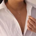 Detailed view of a gold stainless steel Y-shaped necklace with white crystals on a model - Dangling Pear-Shaped Style (6293350355371) / Gold