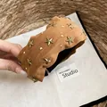 Primer plano detallado de una diadema ancha de tela camel con tachuelas de estrellas doradas - Diadema Café Oscuro