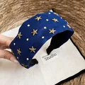 Detalle de los adornos de estrellas doradas en una diadema ancha de tela azul retro - Diadema-Azul