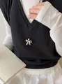 Detail van zilveren strikhanger aan zwart koord met minimalistische kleding. - Zilveren Hanger Met Zwart Touw