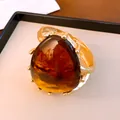 Detailansicht eines markanten bernsteinfarbenen Harzarmreifs mit strukturiertem Goldrahmen - Armreif-Gold-Kaffee