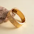 Detail van gouden vierkante armband met een opvallende textuur en glanzende afwerking. - Goud
