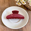 Detailweergave van een stijlvolle rode retro haarclip met witte stippen op een bord - Rood