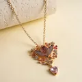 Detail van vintage engel hanger ketting met hars bloemen en roze hartvormige edelsteen - Ketting / Goud