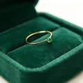 Nahaufnahme eines minimalistischen 1-mm-Goldrings aus Titanstahl mit Zirkonia - Größe 5 / Gold - Grüner Zirkonia