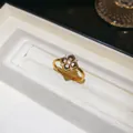 Gros plan d'une bague fleur plaquée or avec émail noir et zircons sur un écrin. - Bague / Or-Noir