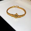 Vue détaillée d'un bracelet jonc plaqué or 24 carats avec un motif floral en émail noir - Bracelet / Or-Noir