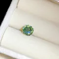 Gros plan d'un clou d'oreille en pierre verte dans un écrin à bijoux en velours blanc - 8mm / Bleu sarcelle