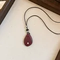 Gedetailleerde weergave van een vintage druppelhanger aan een zwart lederen koord - Zwart/Rozerood