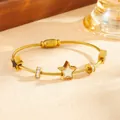 Dettaglio di un bracciale in acciaio al titanio dorato con ciondoli a stella e cristalli - Bracciale Stella in Conchiglia Bianca Dorata (G715)