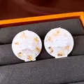 Close-up of elegant round stud earrings with white pearl and gold foil texture - Silver / Gold with White
