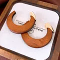 Close-up detail of vintage wooden C-shaped stud earrings with gold metal accents - Gold C-Shaped Earrings / Coffee