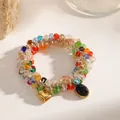 Detailed macro shot of a multi-color beaded elastic bracelet with a gold heart charm. - Heart Black Oval Pendant (M202) / Colorful
