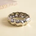 Detailopname van een dikke zilveren metalen armband met onregelmatige plooitexturen. - Gedraaide Textuurstijl / Zilver