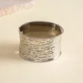 Gedetailleerd close-up van een zilveren getextureerde metalen manchetarmband met golven - Brede Golvende Stijl / Zilver