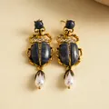 Détail macro exquis de boucles d'oreilles scarabée dorées vintage avec strass et perles - Tige d'oreille en argent - Or - Bleu