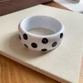 Nahaufnahme eines weißen Y2K-Resin-Armreifs mit markantem schwarzen Punktmuster-Design - Polka Dot Stil / Weiß/Schwarz Punktmuster