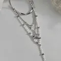 Detailed macro view of silver multi-layered pearl necklace featuring star and heart pendants - Four-Piece Set / Silver