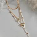 Macro view of gold Y-shaped necklace featuring pearls, zircon, and star charms - Four-Piece Set / Gold