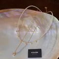 Dettaglio raffinato di set di collane in zircone e perle placcate oro 18k su una conchiglia - Set di Collane (Placcato Oro 18K) / Oro con Bianco