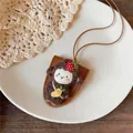 Detailopname van een schattige bruine pluizige schaap hanger met aardbei op leren koord - Koffie Lam Stijl / Bruin