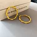 Close-up of gold bamboo joint hoop earrings with zircon accents on a neutral background. - Gold
