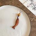 Minimalistische Fisch-Halskette aus Holz mit Zen-Ästhetik und einem braunen Kordel - Gebogener Fisch / Braun