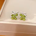 Gedetailleerde opname van groene glazen bloemoorbellen met zirkonia steentjes. - Zilveren oorsteker-Groen