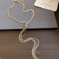Gedetailleerd beeld van de gouden geknoopte ketting met meerstrengs kwastjes op een bord. - Alleen Ketting / Goud