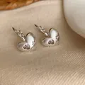 Primer plano detallado de elegantes pendientes de corazón de plata cepillada con incrustaciones - Plateado