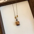 Detailopname van een schattige handgemaakte houten beerhanger aan een vintage ketting. - Beer Stijl (2#)