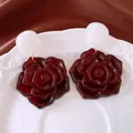 Makroansicht von Vintage-Harzrosen-Ohrringen mit dunkelroter Blume und weißem Bolzen - Weiß und Tiefrot