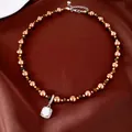 Tigerauge- und Perlenkette mit funkelndem quadratischem Zirkonia-Anhänger auf brauner Seide. - Kaffeebraun